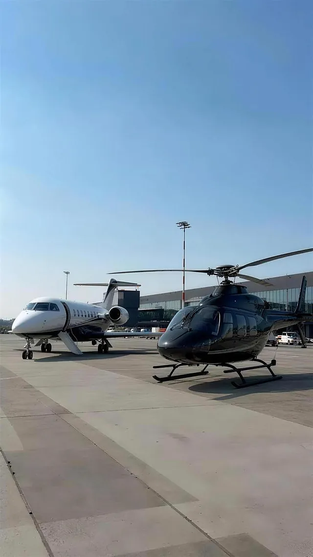 A black helicopter beside a white private jet on the airport apron