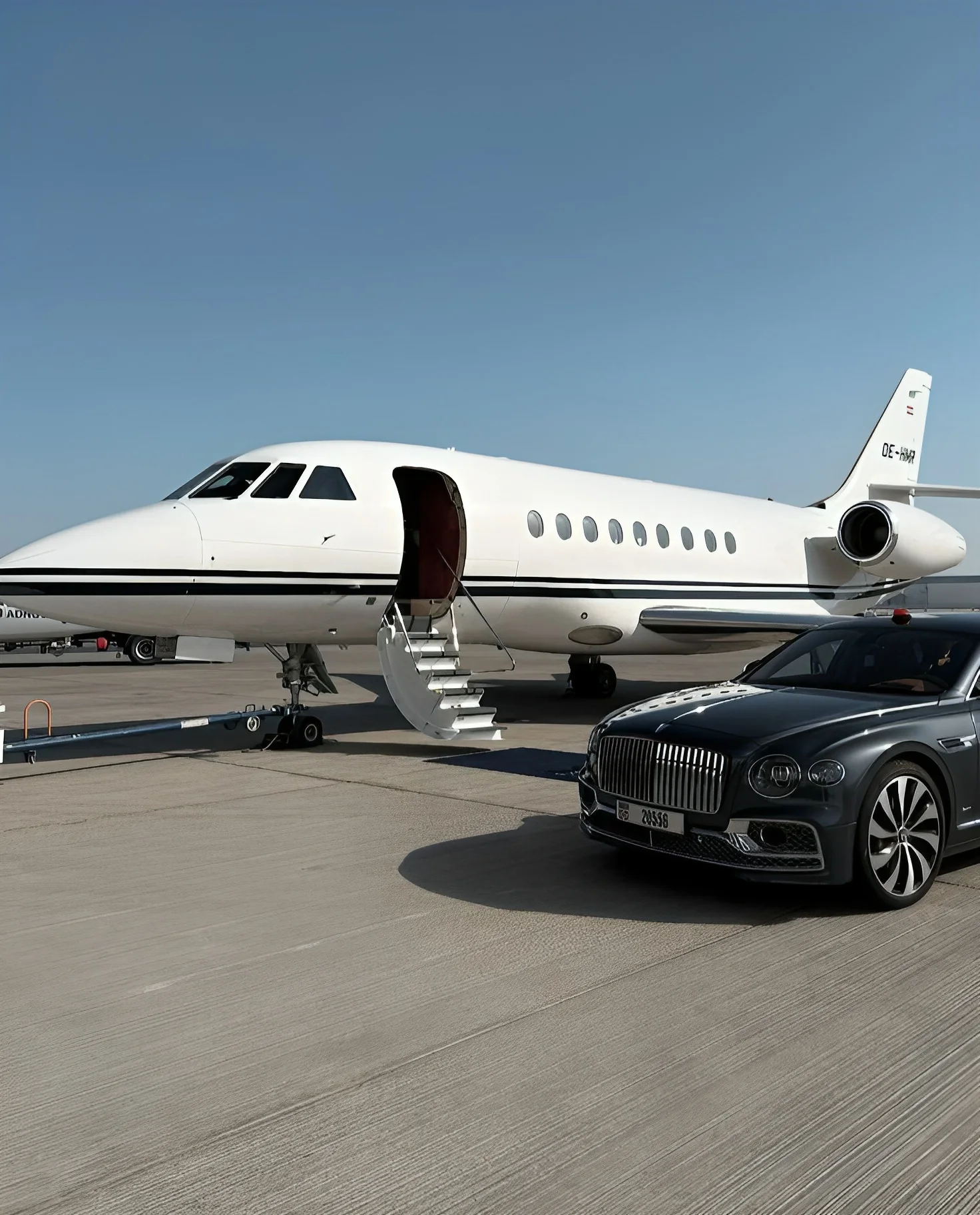 A private jet with its stairs down, a chauffeured sedan waiting alongside
